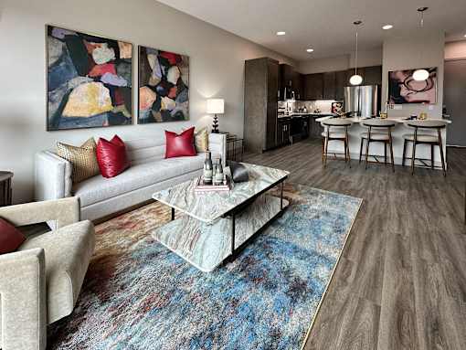 A modern living room with a grey sofa, a coffee table, and a dining table set up.