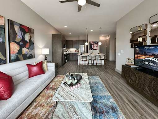A living room with a white couch and a coffee table with a vase on it.