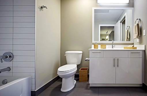 A white toilet sits in a bathroom next to a white bathtub.