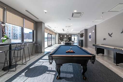 A pool table is in the middle of a room with a long table and chairs.