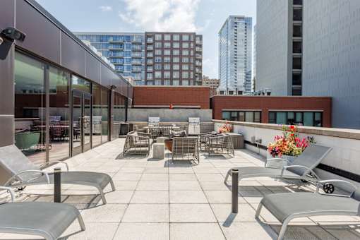 A patio with chairs and a table with flowers on it.