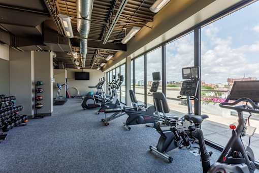 A gym with a row of exercise bikes and a television.
