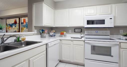 Bright white kitchen with tile floors at Preston Village Apartments in north Dallas
