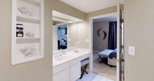 Luxury apartments with spacious bathrooms with tiled floors, linen closet, oval soaking tubs, built-in vanity, cultured marble vanity, glass shower and white cabinets in at The Saxony Apartments
