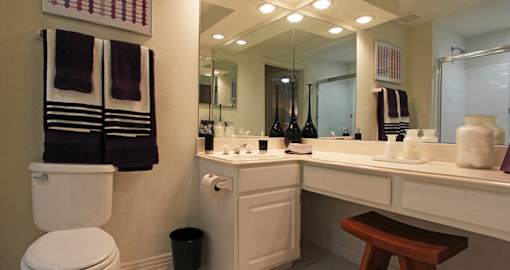Spacious bathroom with oval soaking tub with glass enclosure, cultured marble vanity, glass shower, and built-in vanity at Tuscany Oaks Apartments in Houston.