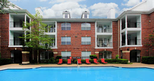 Luxury swimming pool with spacious sundeck, beautiful landscaping, and poolside lounge seating at Tuscany Oaks Apartments in Houston.