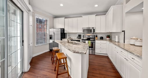 Spacious kitchen with island, granite countertops, custom home cabinets, smooth glass top stove, spacious pantries, and stainless-steel appliances at Tuscany Villas in Houston.
