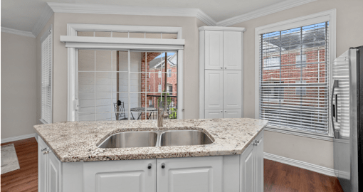 Spacious kitchen with island, granite countertops, custom home cabinets, French doors, smooth glass top stove, spacious pantries, breakfast bar and stainless-steel appliances at Tuscany Row Townhomes in Houston.