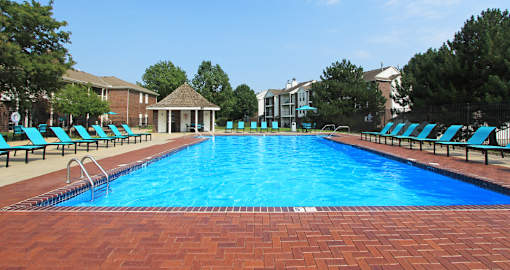 Huge swimming pool with spacious sundeck, poolside lounge chairs, beautiful landscaping, and scenic views at The Vanderbilt Apartments in Omaha, Nebraska