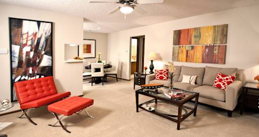 A living room with a red chair and a grey couch.