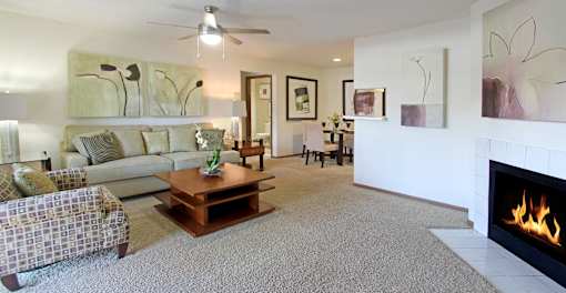 Spacious living room with woodburning fireplace and dining room area at Tanglewood Apartments in Lincoln Nebraska