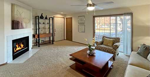 Spacious living room with woodburning fireplace, large patio door windows and patio at Tanglewood Apartments in Lincoln Nebraska