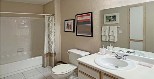 Spacious bathroom with tiled floor, tiled shower with bathtub, extra cabinet space and linen closet at Tanglewood Apartments in Lincoln Nebraska