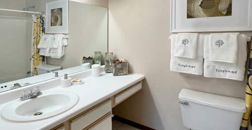 Bathroom with tiled floor, tiled shower with bathtub, cabinet space and built-in vanity at Tanglewood Apartments in Lincoln Nebraska