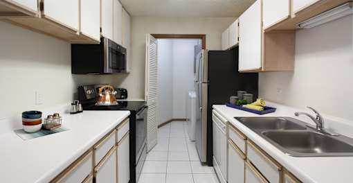 Spacious kitchen with lots of cabinet space, lots of counter space, tiled floors, bright white kitchen, full-sized washer and dryer in separate laundry room at Tanglewood Apartments in Lincoln Nebraska