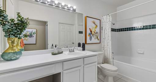 Spacious bright white bathroom with oversized garden tub and built-in vanity at Village on the Parkway Apartments