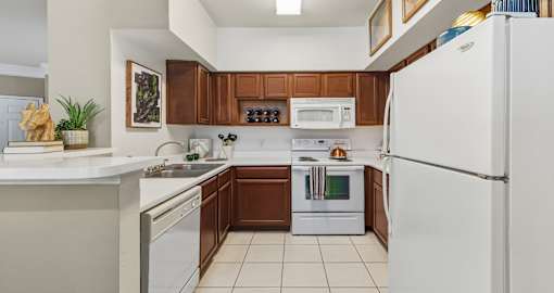 Spacious kitchen with designer white appliances and tile floors at Village on the Parkway Apartments