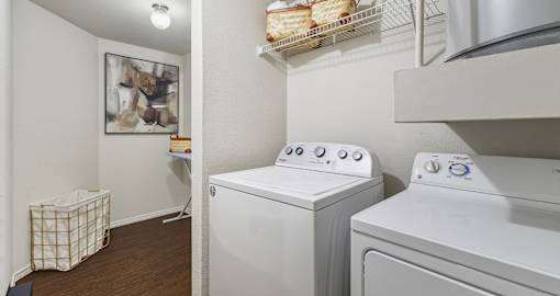 Spacious laundry area with full-size washer and dryer and extra storage space at Village on the Parkway Apartments.