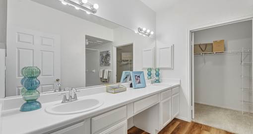 Spacious bathroom with double-sink, built-in vanity, extra-large mirror, lots of cabinet space, and tiled shower at Village on the Parkway Apartments in Houston Texas