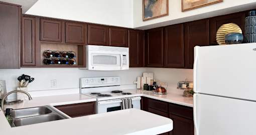 Spacious kitchen with designer white appliances and tile floors at Village on the Parkway Apartments