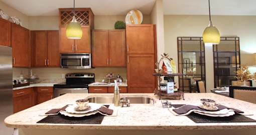 Luxury apartments next to the Galleria in Dallas with granite countertops, stainless steel appliances, built-in wine rack, kitchen island, and porcelain tile floor at Villa Piana Apartments in Dallas