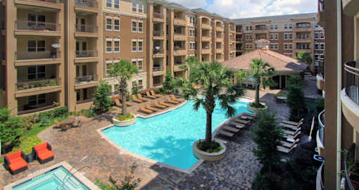 Luxury apartments with palm trees, spa, hot tub, spacious sundeck with poolside lounge chairs, beautiful landscaping, and fountains at Villa Piana Apartments in Dallas