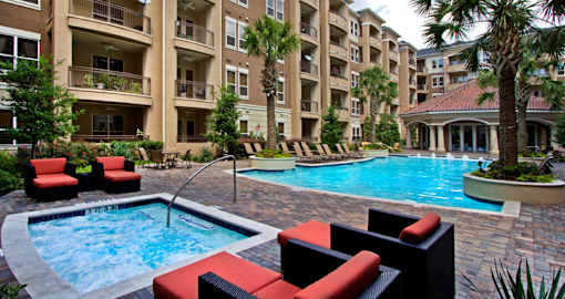 Luxury apartments with resort-style pool, spa, palm trees, spacious sundeck with poolside lounge chairs, grilling station, and fountains at Villa Piana Apartments in Dallas