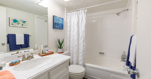 bright white bathroom with tiled shower and lots of cabinet space at Waters of Winrock Apartments in Houston TX