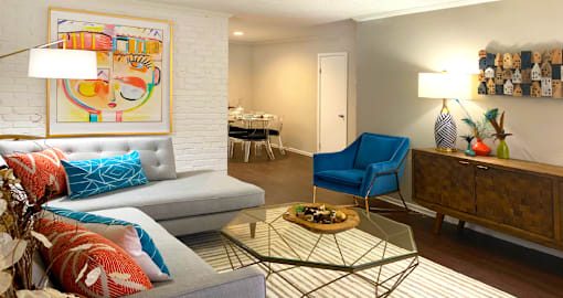 Spacious one and two bedroom floor plans with white brick accent walls and wood plank floors at Waters of Winrock Apartments in Houston.