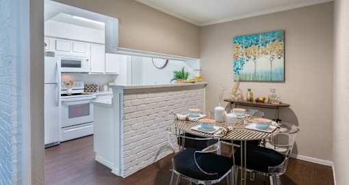 Spacious one and two bedroom floor plans with white brick accent walls and wood plank floors at Waters of Winrock Apartments in Houston