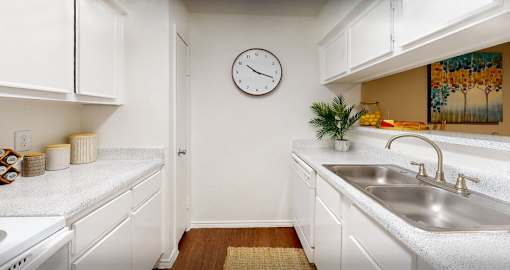 Bright white kitchens with wood plank floors at Waters of Winrock Apartments in Houston