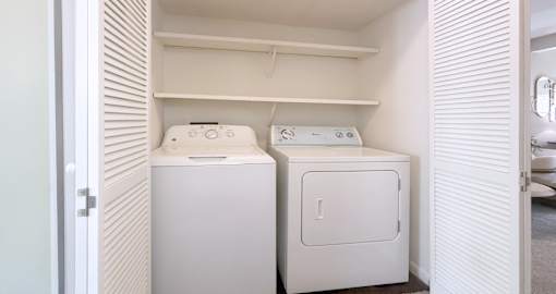 Two white washing machines in a small laundry room.