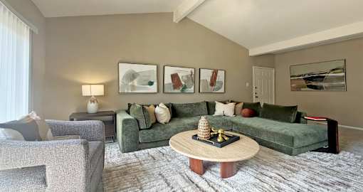 A living room with a green couch, a grey armchair, a coffee table, and a painting on the wall.