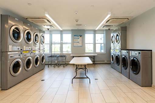 A laundromat with a row of washing machines and a table in the middle.