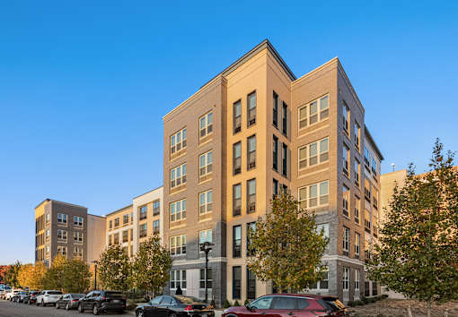 A multi-story building with a parking lot in front.