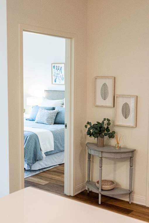 A bedroom with a bed and a table with a plant on it.