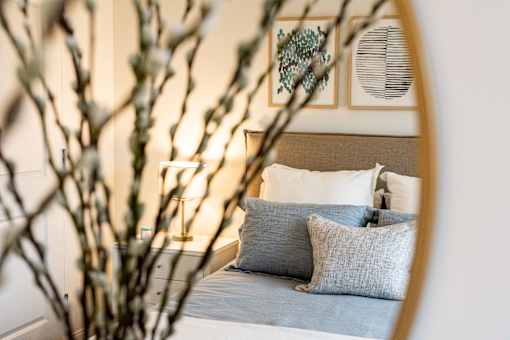 A bedroom with a bed, pillows, and a mirror.