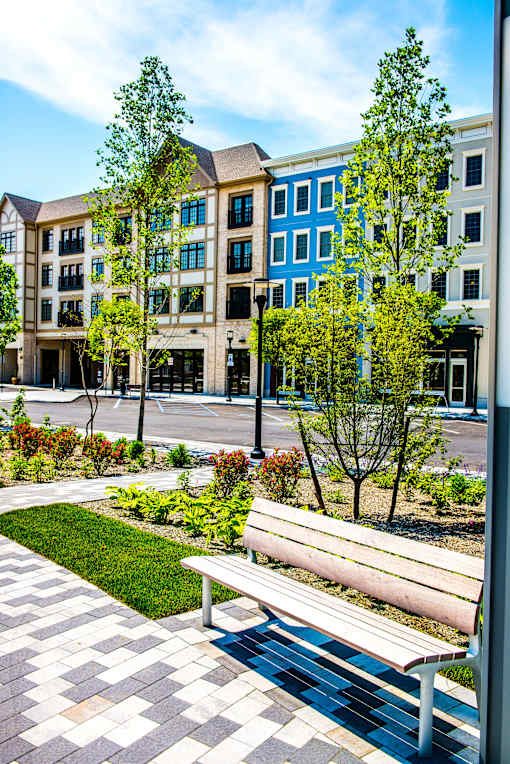 A bench is in front of a building with a tree in front of it.