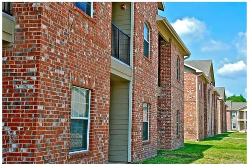 a brick building with green grass and a blue sky in the background