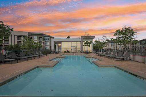 A large swimming pool surrounded by lounge chairs and trees.