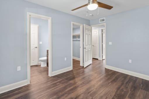 an empty living room with blue walls and a ceiling fan