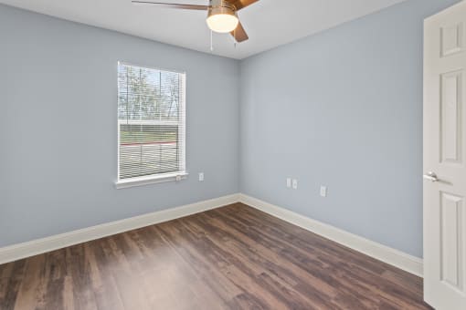 an empty room with wood floors and a window