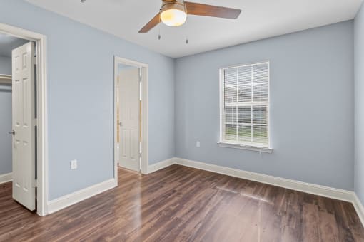 an empty room with blue walls and a ceiling fan