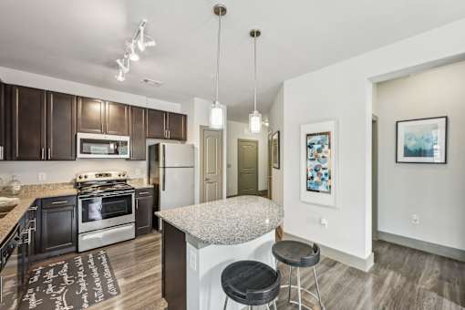 A kitchen with a granite countertop and a black and white rug on the floor.