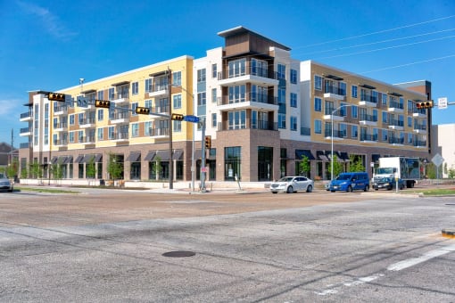 a large apartment building on the corner of a street with cars parked in front of it