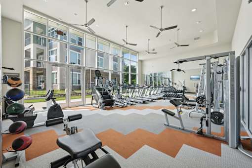 A gym with a variety of equipment including weights and cardio machines.
