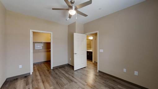 A room with a ceiling fan and wooden floors.