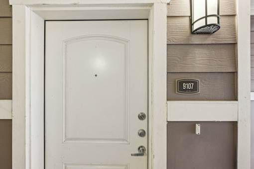 A white door with a number plate on the wall.