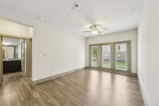 A bright room with wooden floors and a ceiling fan.