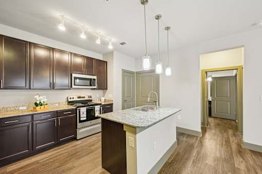 A kitchen with dark brown cabinets and a white granite island.